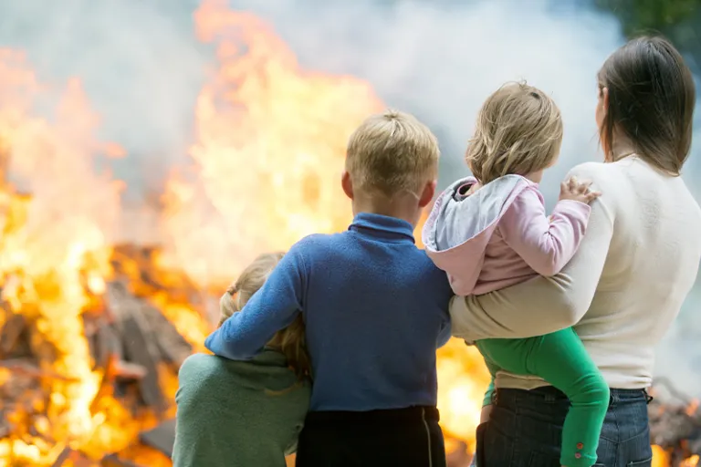 Famille vue de dos devant leur maison en feu
