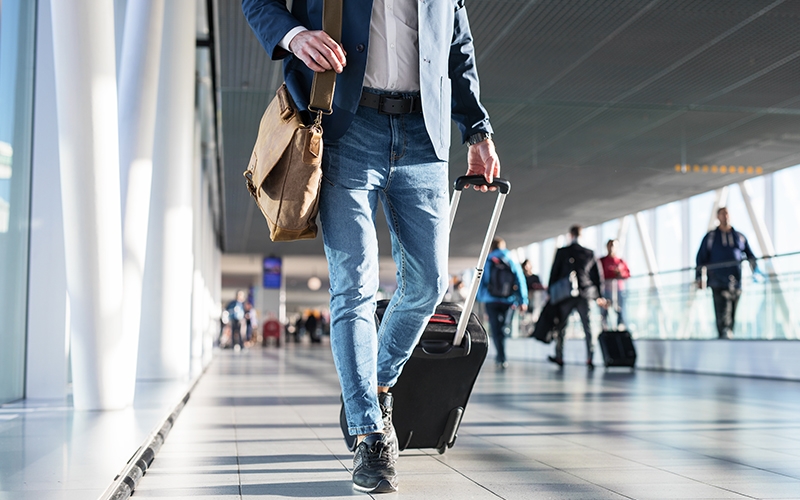 Homme marchant dans un aéroport avec ses bagages.